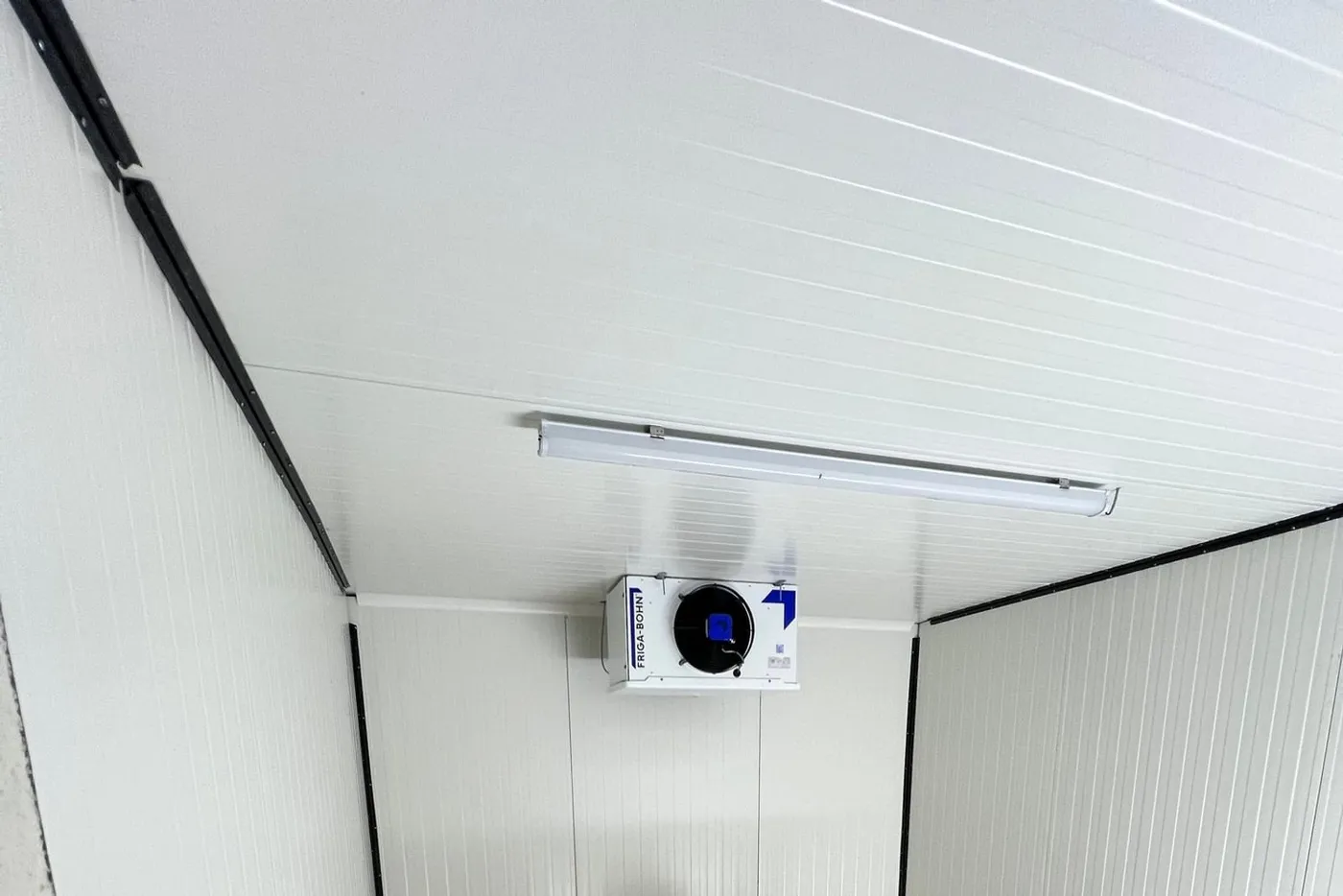 Évaporateur plafonnier en fonctionnement dans une chambre froide en panneaux blancs