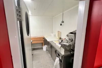 Chambre froide vue depuis sa porte rouge, rayonnages au fond